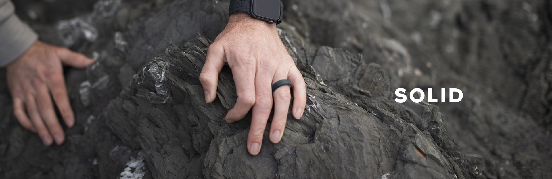 Solid, a man's hand grips a rock and displays his groove ring