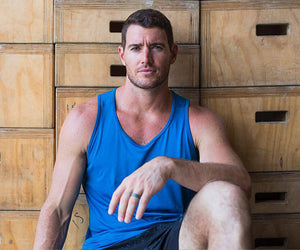 Aaron Hanna sitting against wooden drawers, looking at the camera