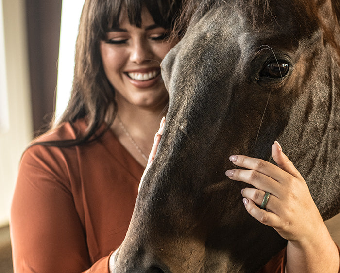 Katie Van Slyke petting a horse wearing a Groove Life ring