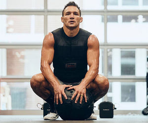 Michael Chandler crouches in workout gear, with a weight ball in front of him
