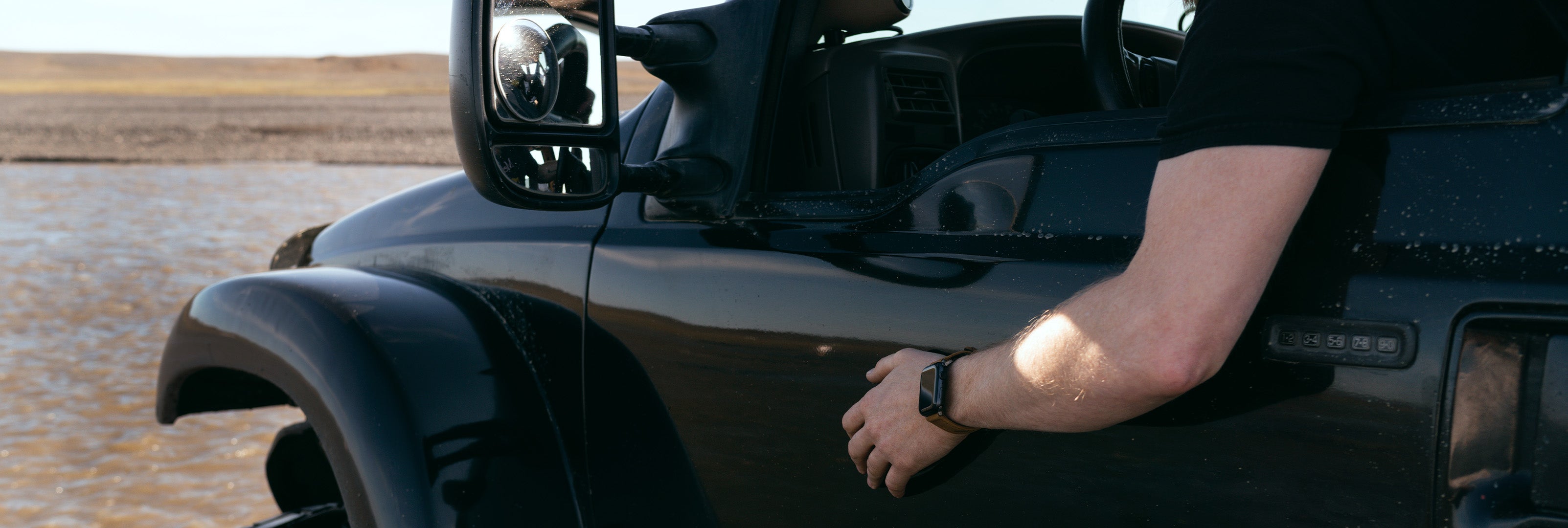 image of the side of a black vehicle, a man's arm hanging out of the window wearing a Groove Life watch band